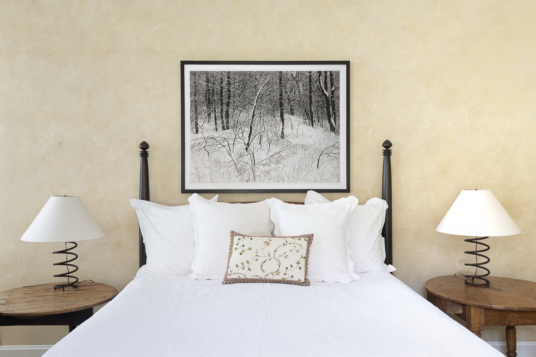 Bedroom with a black-and-white winter-forest etching above the bed
