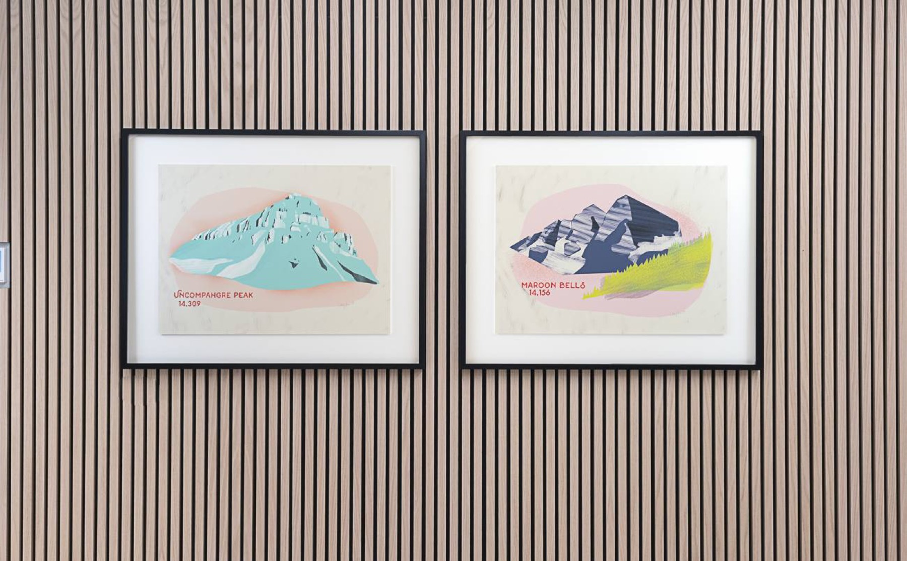 Two framed illustrations of Colorado peaks, Uncompahgre Peak and Maroon Bells, on a slatted wood wall