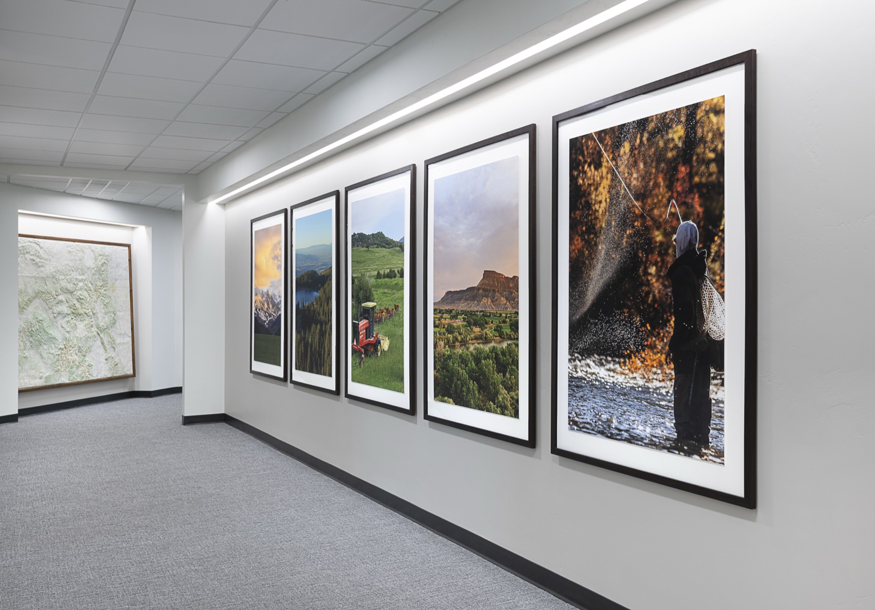 Corridor lined with five large framed Colorado landscape photographs and a relief map at the end