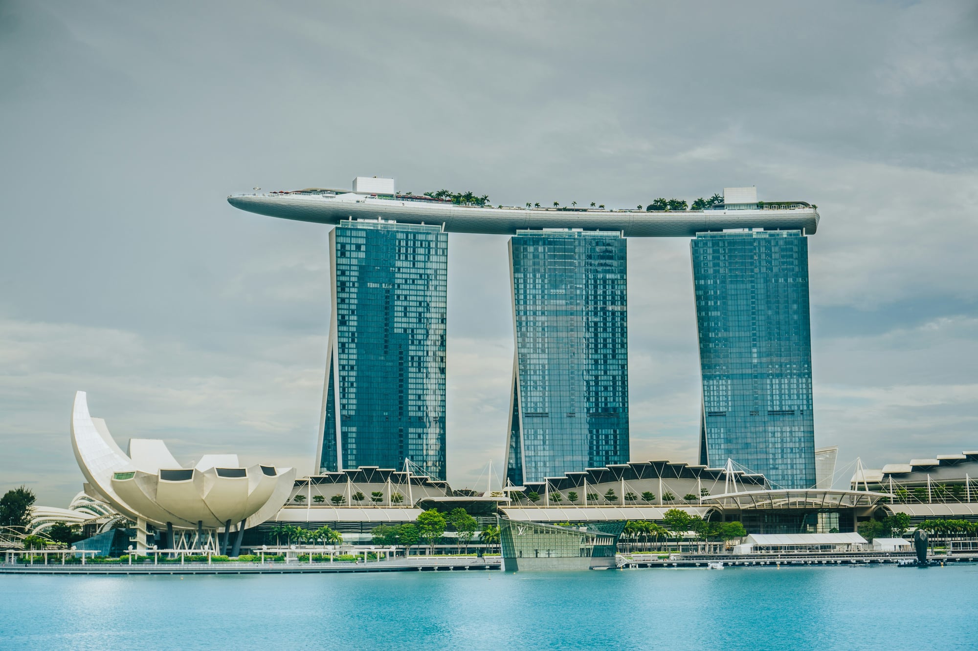 Marina Bay Sands from across the bay: three glass towers joined by the SkyPark, with the ArtScience Museum in front