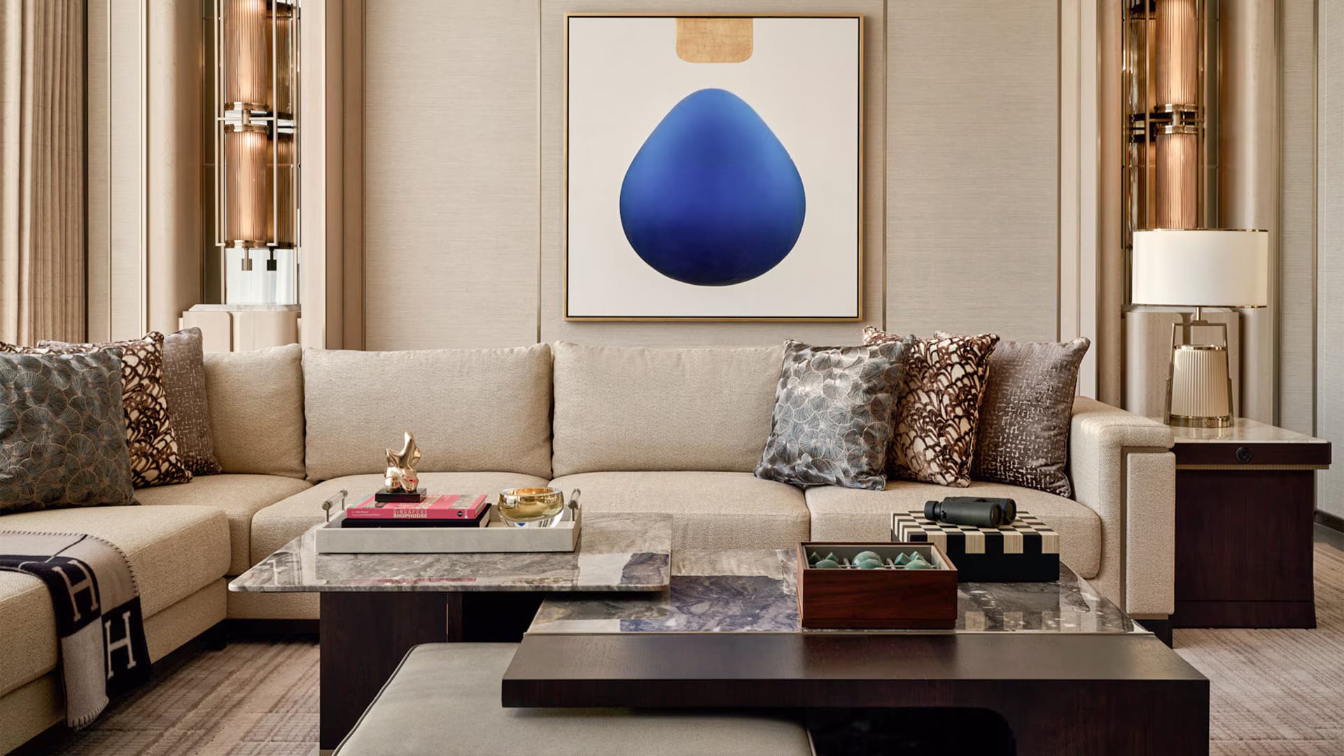 The Presidential Suite lounge: a painting of a single deep-blue drop above a cream sofa with patterned cushions and gold accents