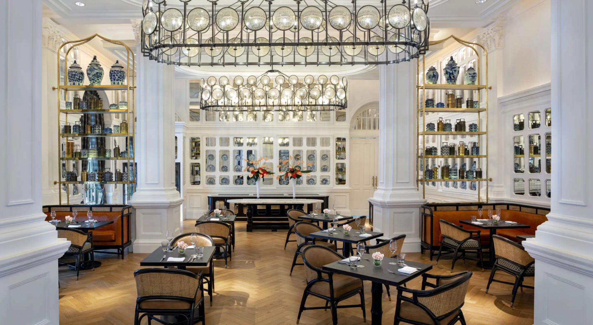 The Tiffin Room at Raffles Singapore: white columns and shelves lined with blue-and-white porcelain beneath a chandelier