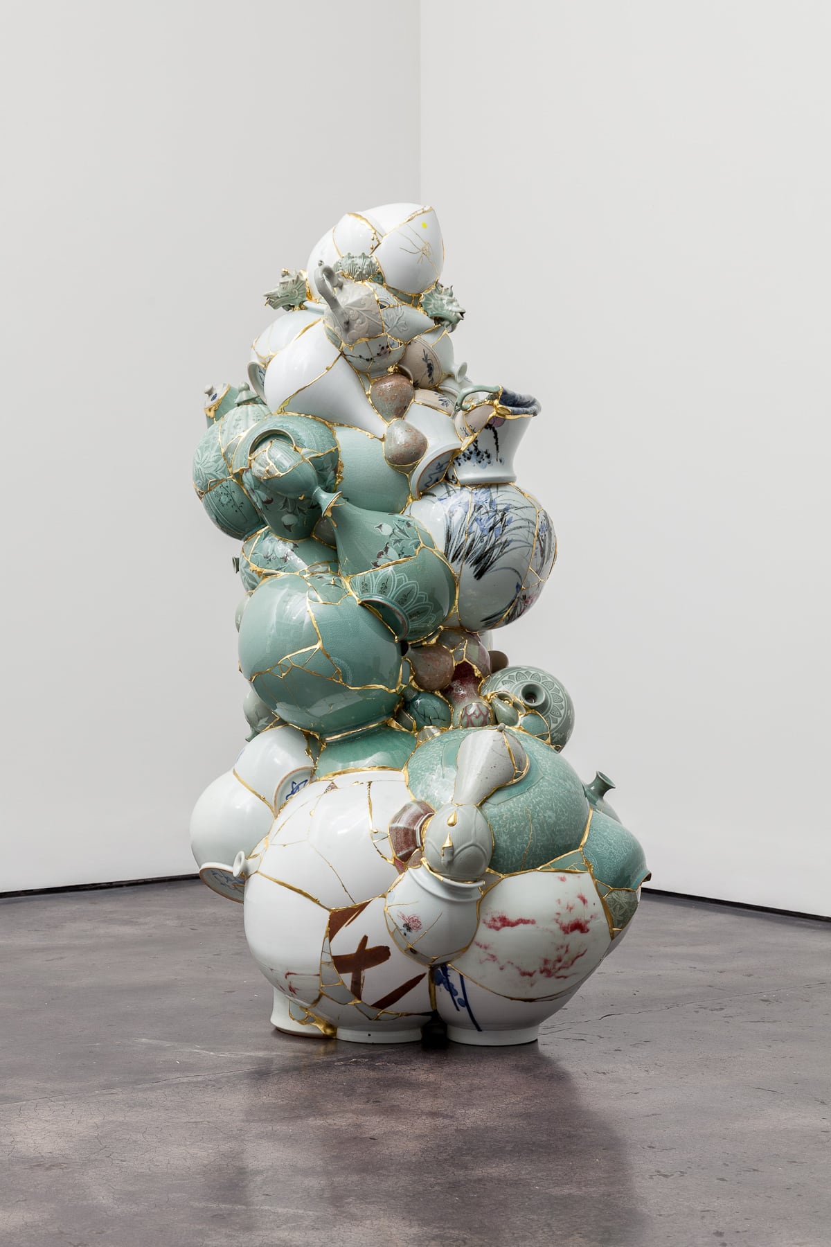 Yeesookyung's Translated Vase: a tall stacked sculpture of celadon and porcelain shards fused with gold seams, in a white gallery space
